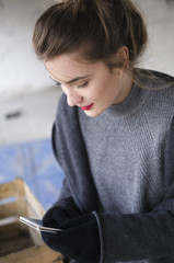 Beautiful smiling young woman holding phone on winter