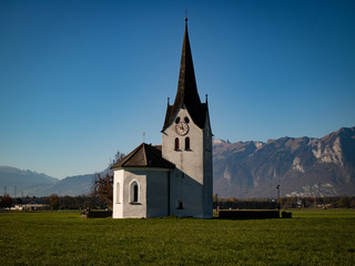 Fototapeta na wymiar Kirche in Brederis vor Bergkulisse