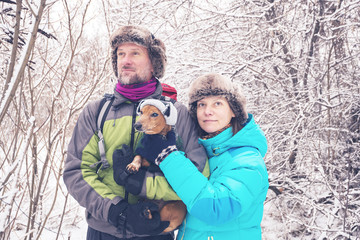 Smiling couple with the small dog, in funny winter hats