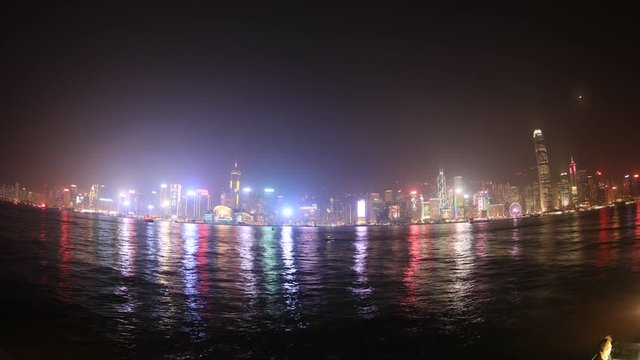 Hong Kong fisheye wide time lapse of skyline with illuminated skyscrapers and red-sail junk boat at night. sea view.
