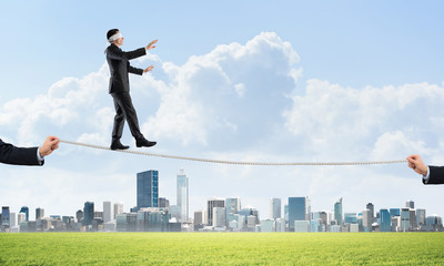 Business concept of risk support and assistance with man balancing on rope