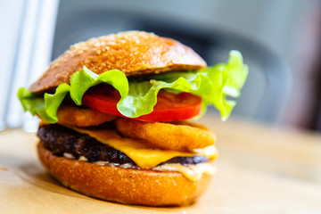 Hamburger with cheese, steak, onion rings and salad.