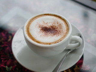 Top view of cappuccino coffee on white cut and on glass table with blur background