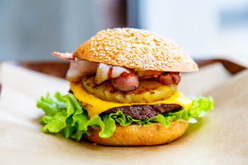 Hamburger with cheese, steak, onion rings, lettuce, pineapple an
