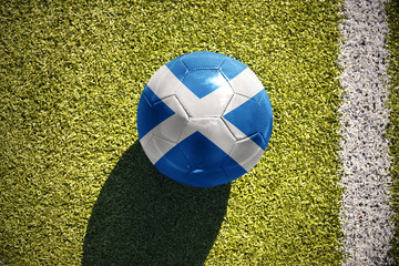 Naklejka premium football ball with the national flag of scotland lies on the field