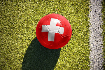 Obraz premium football ball with the national flag of switzerland lies on the field