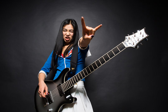 Asian Rock Star Lady Showing Yo Sign While Playing Guitar Isolated On Grey Background In Studio. Rock Music Concept.