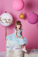 Fototapeta premium Pretty girl child 4 years old in a blue dress. Baby in Rose quartz room decorated holiday.