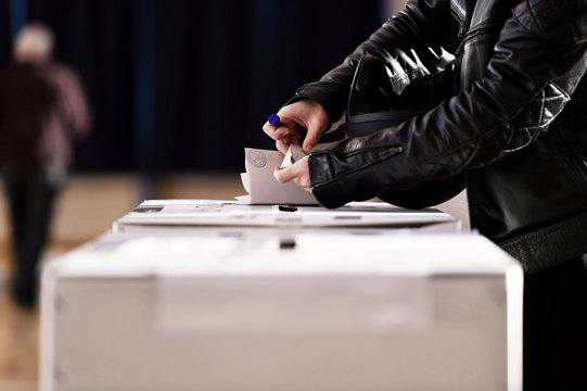 Hand casting a vote into the ballot box