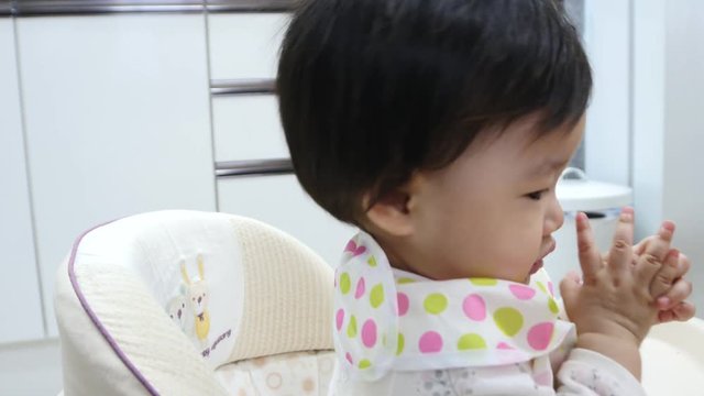 The asian baby girl eating with spoon on stroller
