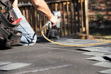 handyman using nail gun to install shingle to repair roof © nd700