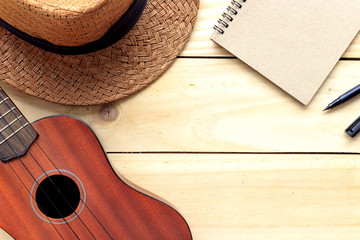 close-up ukulele and hat on wood background. over light