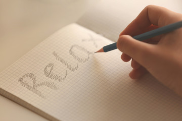 Female hand writing word "relax" in notebook, close up view