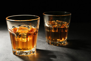 Glasses of whisky on grey textured table closeup