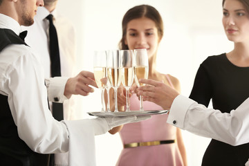 Waiter in uniform serving champagne during buffet catering party