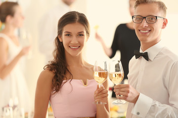 Fototapeta na wymiar Young man and woman with glasses of champagne at party