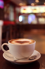 Cup with hot tasty coffee on wooden table in cafe, close up view