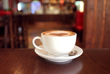 Cup with hot tasty coffee on wooden table in cafe, close up view