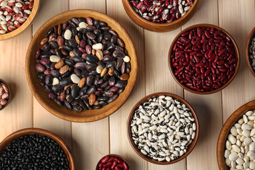 Assortment of haricot beans in bowls on wooden background