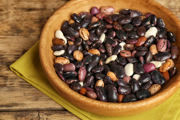 Bowl with dried haricot beans and napkin on wooden table
