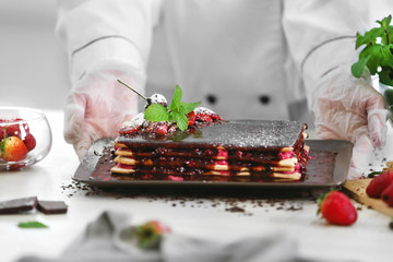 Delicious cake with berries topping, chocolate and mint on kitchen table