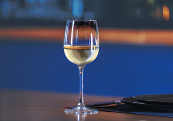 Glass with white wine on table