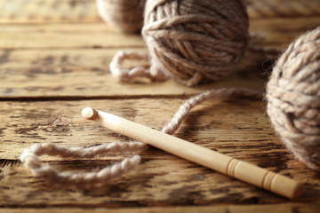 Grey knitting yarn and hook on wooden table, closeup