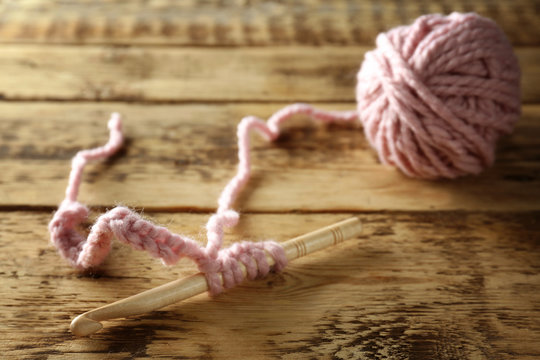 Crochet hook with knitting on wooden table