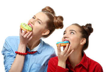 Funny young women eating tasty donuts on white background