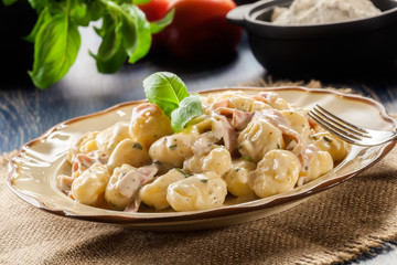 Potato gnocchi, Italian potato dumplings with cheese sauce, ham