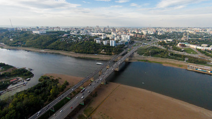 Fototapeta premium Autumn in city. Panoramic aerial view at road, forest, river.