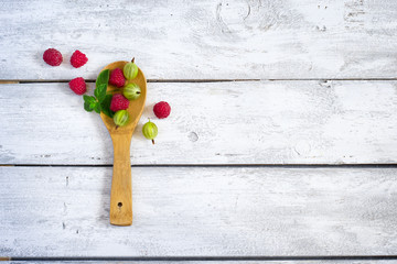 Naklejka na ściany i meble Fresh organic raspberries and gooseberries in a wooden spoon. To