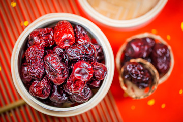 Dried dates in bamboo basket on table on red background.