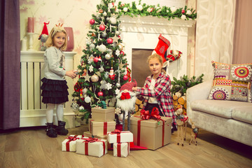 Fototapeta na wymiar Little girls decorating Christmas tree and preparing gifts