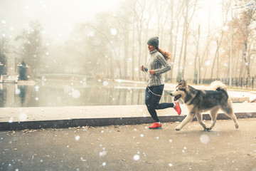 Image of young girl running with her dog, alaskan malamute
