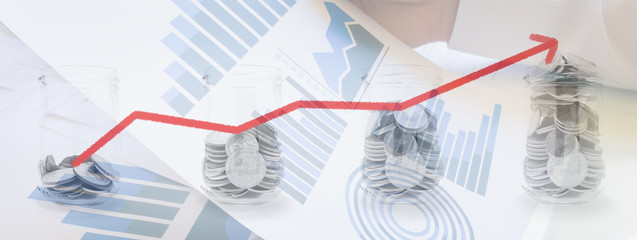 Double exposure of coins in glass bottle with red line graph and data chart report in hand background for financial and business concept.