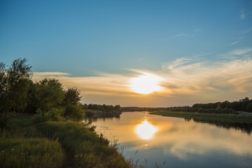 Obraz premium River at sunset time with a yellow sun and clouds