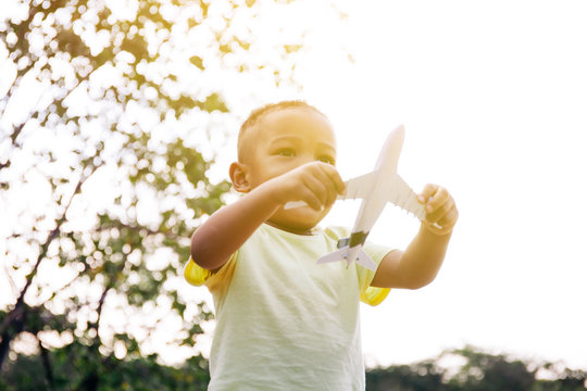 Little Kid Playing With Airplane Toy In Green Park