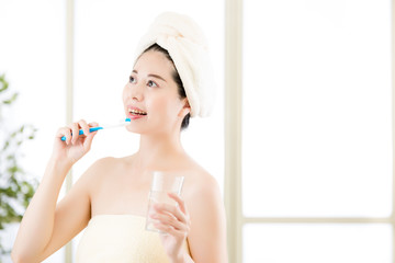 smiling asian woman drying towel on head holding toothbrush