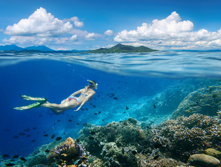 Vrouw zwemt rond een koraalrif omringd door een veelvoud aan vissen op de achtergrond Islands...North Sulawesi, Indonesië.