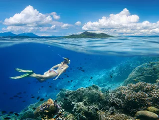 Foto auf Acrylglas Tauchen Frau schwimmt um ein Korallenriff, umgeben von einer Vielzahl von Fischen auf den Hintergrundinseln... Nord-Sulawesi, Indonesien.
