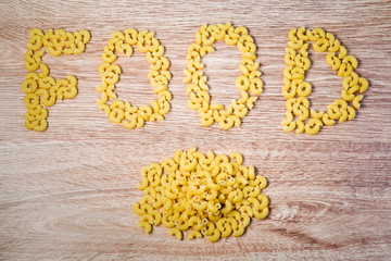 Word food from macaroni pasta on the wooden table.