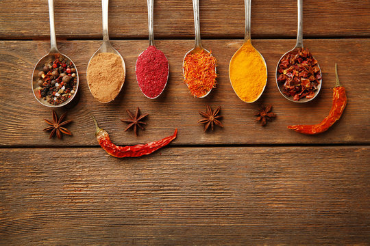 Spices in spoons on a wooden background