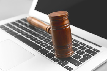 Wooden judge's gavel on laptop keyboard, closeup
