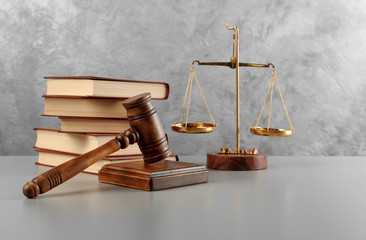 Judge's gavel with books and scales on wall background
