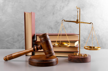 Gavel with books and scales on grey wall background