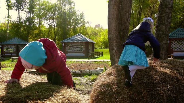 Two beautiful girls are playing in the street on a haystack
