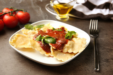 Plate of ravioli with tomato sauce on table