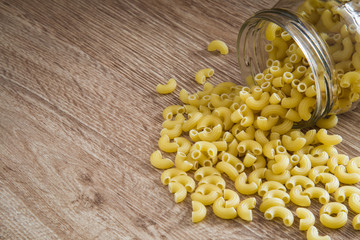 Macaroni pasta on the wooden table. Cooking at home in the kitchen. Healthy eating and lifestyle.