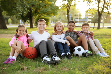 Cute kids with sport balls on green grass